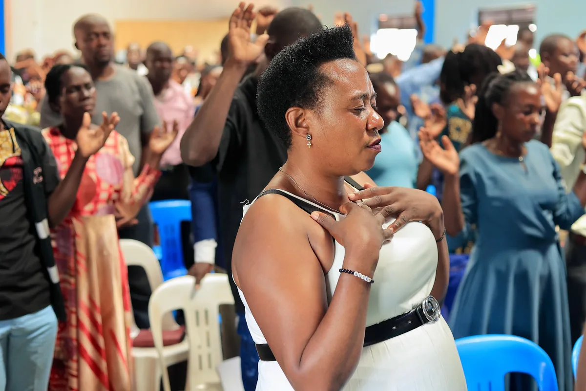 A woman with her hand on her heart during worship