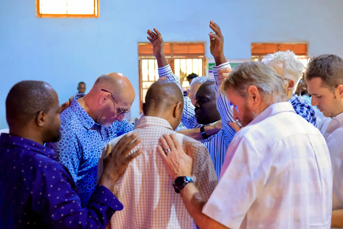 Members praying for one another with hands laid on